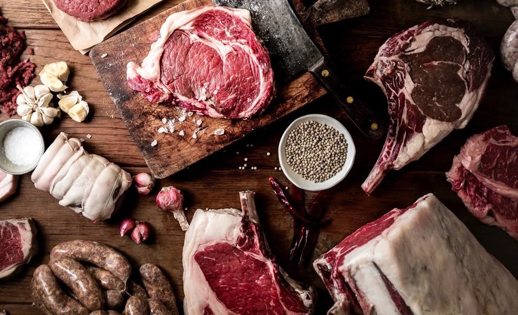 Fresh cut beef, cleaver, and garlic on a butcher's table